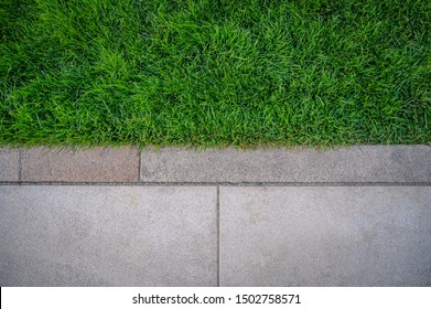 Top View Of Green Grass Texture With Cement Sidewalk.