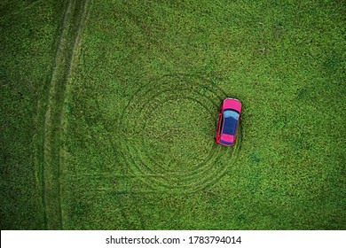 Top View Of A Green Meadow With Grass, Red Car Made Crop Circles. Aerial Photography