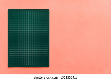 Top view of green rubber cutting mat on the left side over pink color paper background. Background with copy space. - Powered by Shutterstock