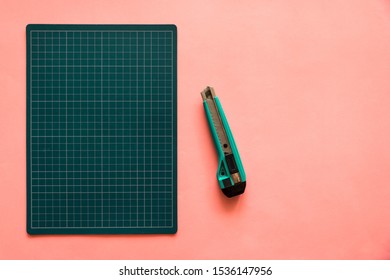 Top view of green rubber cutting mat with green cutter on the left side over pink color paper background. Background with copy space. - Powered by Shutterstock