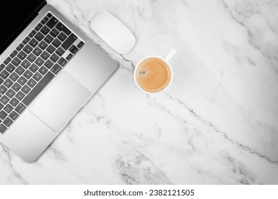 Top view of grey laptop computer on white marble background. Coffee cup, white mouse, flat lay, copy space.