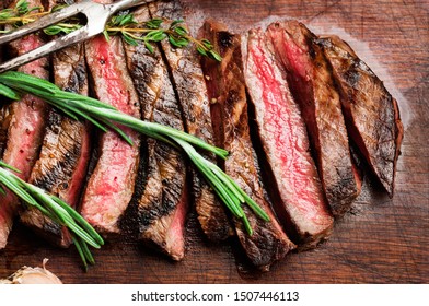 Top View Of Grilled And Sliced Flank Steak On Wooden Board