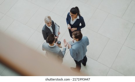 Top view of group of business people in suits discussing financial graphs in lobby of business center - Shutterstock ID 2171993447