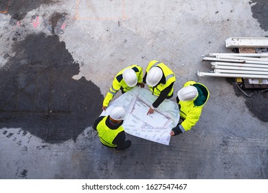 A top view of group of engineers with blueprints standing on construction site. - Powered by Shutterstock