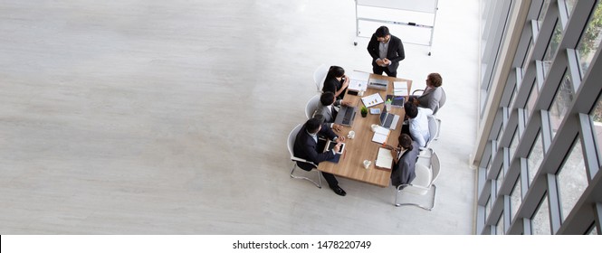 Top View Of Group Of Multiethnic Busy People Working In An Office, Aerial View With Businessman And Businesswoman Sitting Around A Conference Table With Blank Copy Space, Business Meeting Concept