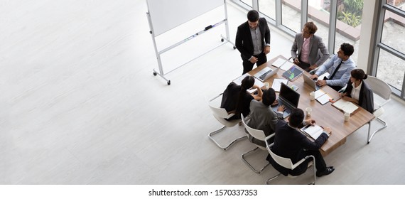 Top View Of Group Of Multiethnic Busy People Working In An Office, Aerial View With Businessman And Businesswoman Sitting Around A Conference Table With Blank Copy Space, Business Meeting Concept