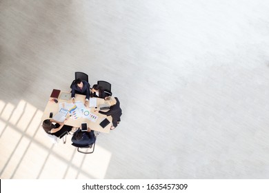 Top View Of Group Of Multiethnic Busy People Working In An Office, Aerial View With Businessman And Businesswoman Sitting Around A Conference Table With Blank Copy Space, Business Meeting Concept