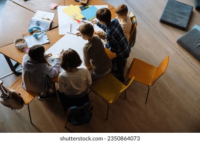 Top view of group of school children drawing with pencils during art lesson in classroom - Powered by Shutterstock