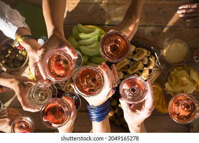 Top view of group of women hands toasting together with glasses of wine. Friends celebrating at restaurant. Top view of friends raising hands and toasting drinks glasses for celebration at hotel