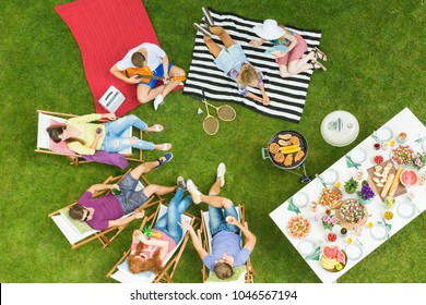 Top View Of Group Of Young Friends Having Summer Barbecue Party In The Backyard With Grill And Table Full Of Delicious Food