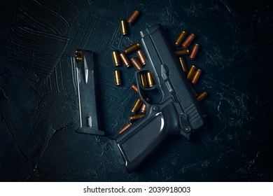 Top view of gun and cartridge with bullets. Weapons on concrete table. Pistol for defense or attack. Concept of crime ammunition and physical evidence. Firearms on dark background.