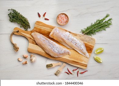 Top View Of Haddock Fillet With Seasoning On Wooden Cutting Board