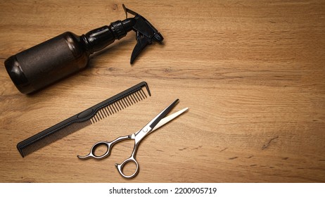 Top View Of Hairdressing Tools In Close-up On A Wooden Background. Wallpaper For A Barbershop. Professional Hair Clippers, Water Pulverizer.