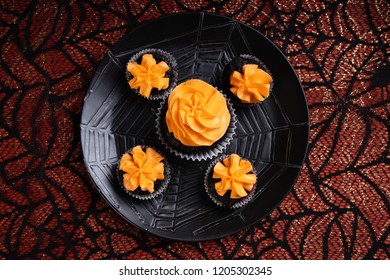 Top View Of Halloween Chocolate Cupcakes With Orange Frosting And A Spider On Top With Four Mini Cupcakes Sitting On A Black Spiderweb Plate