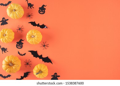 Top view of Halloween crafts, yellow pumpkin, ghost, bat and spider on orange background with copy space for text. halloween concept.