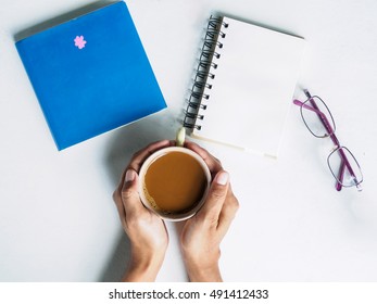 Top View Of Hand Holding Coffee Cup With Workplace  On White Desk