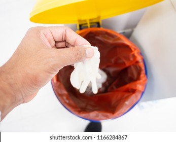 Top View Hand Holding Medical Gloves Dispose And Infectious Waste In Red Plastic Bag Infection Bin.Infectious Waste Control Concept.
