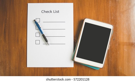 Top View Of Hand Holding Pen On Check List Paper With Tablet