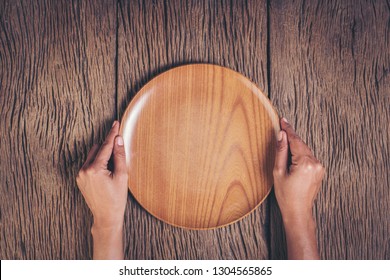 Top view hand holding plate on wood background