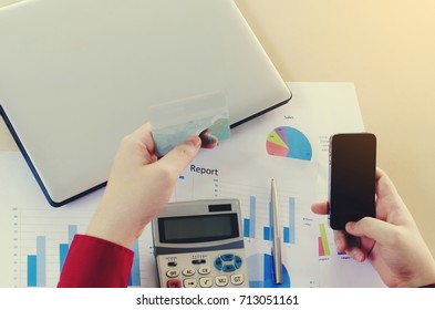 top view of hand holding smart phone and paying with credit card with laptop, expenses chart report and calculator on desk at home office, online payment, shopping online, lifestyle technology concept - Shutterstock ID 713051161