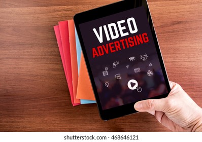 Top View Of Hand Holding Tablet With Video Advertising Word Over Color Notebook On Wooden Table Top,Digital Business Concept