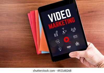 Top View Of Hand Holding Tablet With Video Marketing Word Over Color Notebook On Wooden Table Top,Digital Business Concept