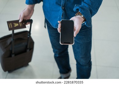 Top view hand man passenger showing passport issue and e-ticket to flight. Touris man showing passport and boarding pass on mobile phone. Businessman showing smartphone online air ticket at airport. - Powered by Shutterstock