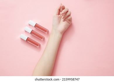 Top view of hand model holding lipstick in pink background for cosmetic advertising