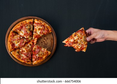 Top view of hand take homemade pizza on black background