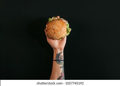 top view of hand with tattoos holding delicious burger with turkey on black