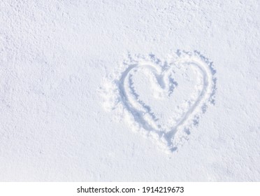 Top view, hand-drawn a heart shape on natural pure white soft snow surface in a cold weather day. Symbol of love in winter holiday season. Romantic outdoor concept for Valentine's day with copy space.