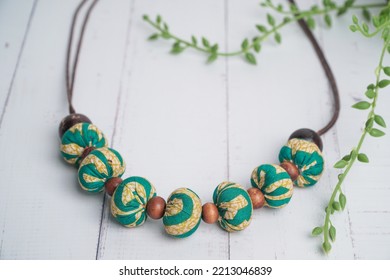 Top View Handmade Fabric Necklace With Coconut Shell Beads On White Wooden Table. Etnic Handmade Jewelery.