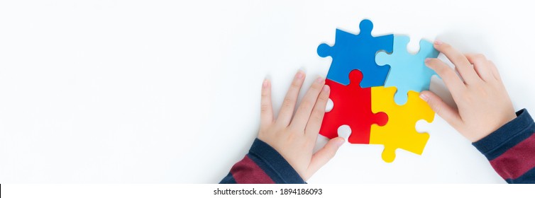 Top view hands of a little child arranging color puzzle symbol of public awareness for autism spectrum disorder. World Autism Awareness Day, ASD, Caring, Speak out, Campaign, Togetherness. Banner. - Shutterstock ID 1894186093
