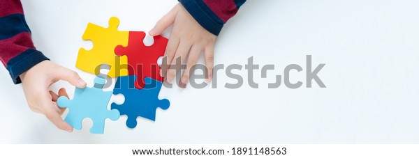 Top view hands of a little child arranging color
puzzle symbol of public awareness for autism spectrum disorder.
World Autism Awareness Day, ASD, Caring, Speak out, Campaign,
Togetherness. Banner.