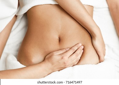 Top view of hands massaging female abdomen.Therapist applying pressure on belly. Woman receiving massage at spa salon - Shutterstock ID 716471497