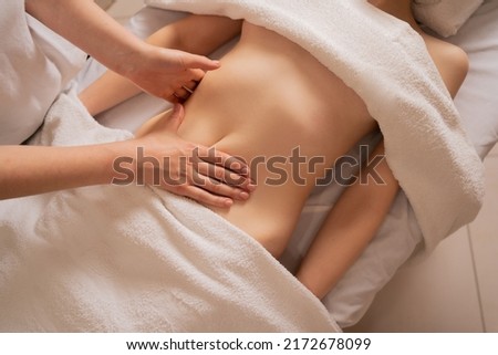 Top view of hands massaging female belly. Therapist applying pressure on the abdomen. lymphatic drainage massage. Woman getting a massage at the spa