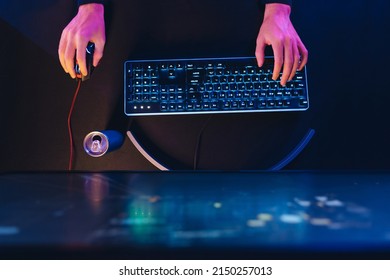 Top View Of Hands Of Pro Cyber Sport Gamer Playing Shooter Game With RGB Keyboard And Computer Mouse. Gamer's Hands, Professional Gaming Setup And Energy Drink. Close Up. Neon Color. Cyber Sport