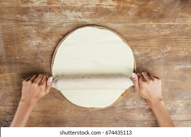 Top View Of Hands Rolling Pizza Dough With Pin On Table