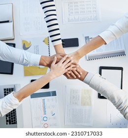 Top view, hands stack and table in office for motivation, team building and collaboration with proposal. Business people, solidarity and together for teamwork, group vision and paperwork on desk