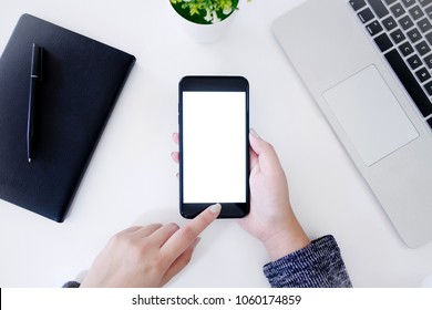 Top View Of Hands Using Blank Screen Mobile Smart Phone With Notebook And Laptop