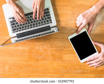 Top view of hands using laptop and tablet on wooden table
