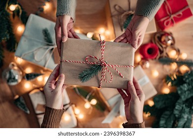 Top view - hands of woman getting surprise handmade red Christmas gift from her girlfriend on Christmas decoration background, Gives a gift, Merry Christmas and Happy Holidays! - Powered by Shutterstock