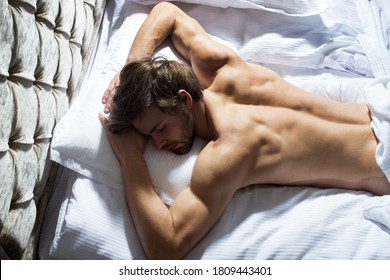 Top View Of Handsome Young Man Sleeping On A Bed In His Bedroom At Night. Waist Up Portrait Of Muscular Handsome Man Laying On Stomach In Bed And Having Nap Embracing The Pillow