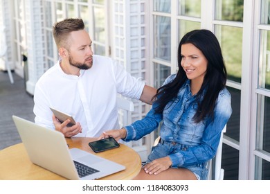 Top View Of A Happy Beautiful Girl Just Paid A Purchase In An Online Store With A Guy's Credit Card. He Received A Text Message On His Tablet About Writing Off Funds, Angrily Looks At His Girlfriend.