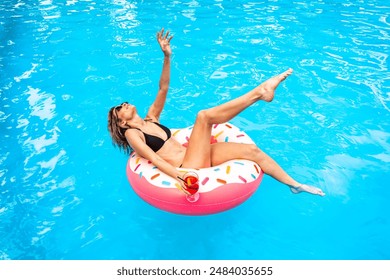 Top view of happy lady swimming on the inflatable ring in the pool and holding cocktail. Copy space. Summer, vacation and lifestyle concept - Powered by Shutterstock