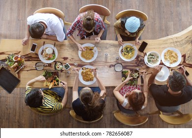 Top view of happy people gathering for eating food together and enjoying the party and communicate with family and friends at table on holiday, soft focus background