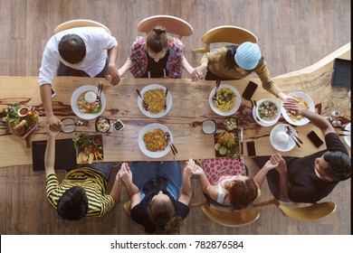 Top view of happy people gathering for eating food together and enjoying the party and communicate with family and friends at table on holiday, soft focus background - Shutterstock ID 782876584