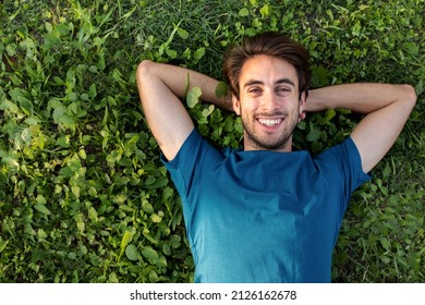 Top view of happy smiling young man relaxing lying on grass looking at camera. Copy space. - Powered by Shutterstock