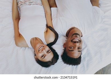 Top view happy young couple two man woman family in casual white clothes lying in bed look camera rest relax spend time together in bedroom lounge home house wake up dream be lost in reverie good day