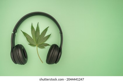 Top View Of Headphones And Cannabis Leaf Isolated A Green Background With Copy Space For Text.